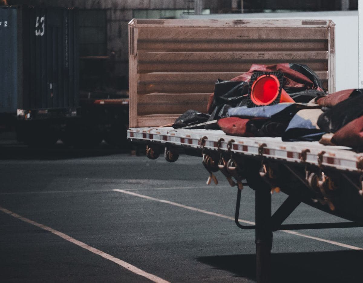 Flatbed trailer with tarps and securement gear at a terminal